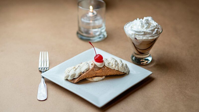 Cannoli dessert with coffee drink topped with whipped cream